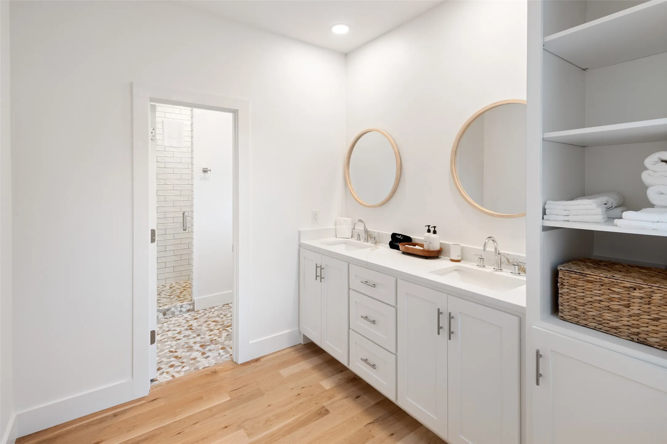 Bathroom with a tile shower, vanity, and wood-type flooring