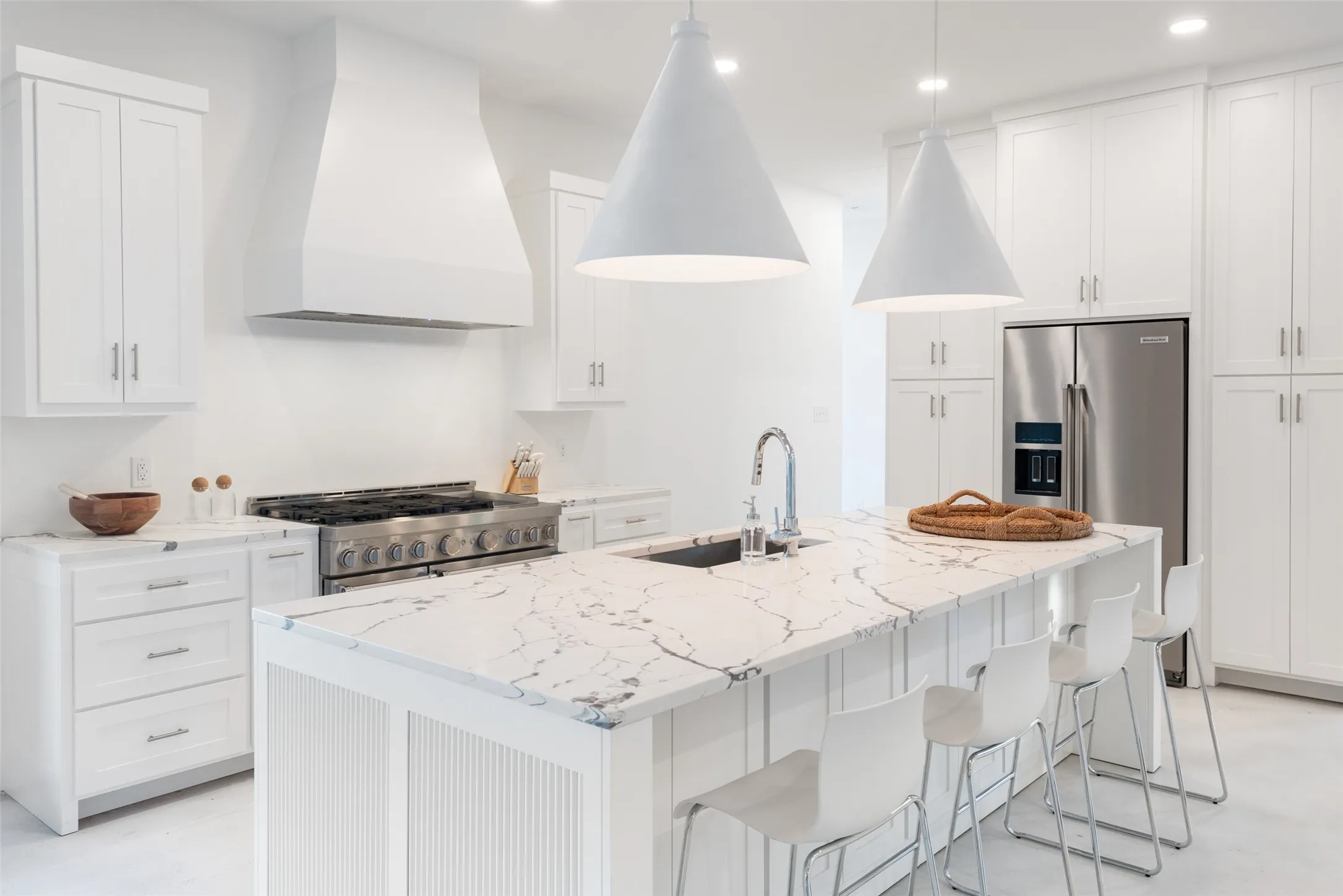 Kitchen with appliances with stainless steel finishes, a kitchen island with sink, custom range hood, sink, and decorative light fixtures