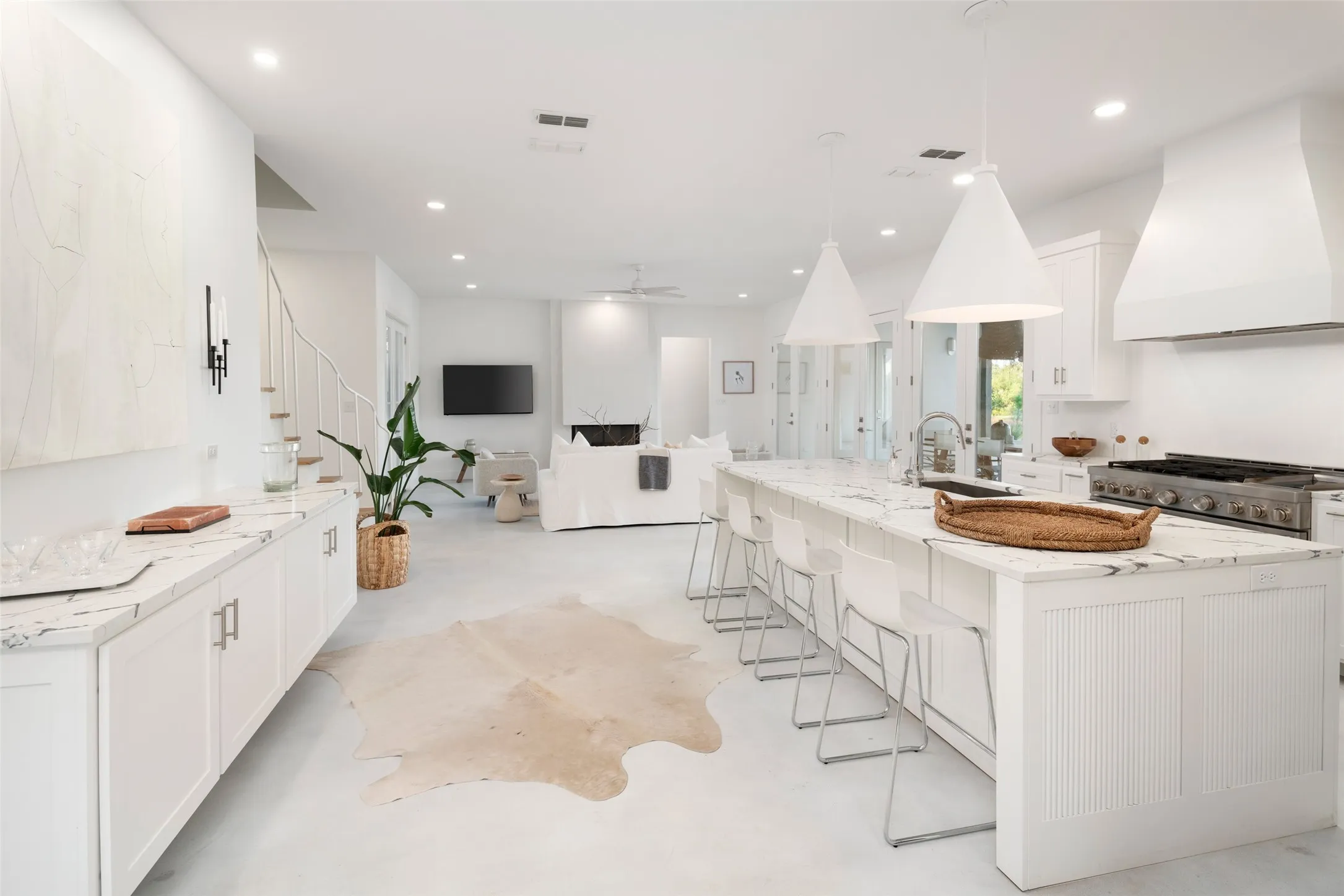 Kitchen featuring a spacious island, sink, custom exhaust hood, and white cabinets