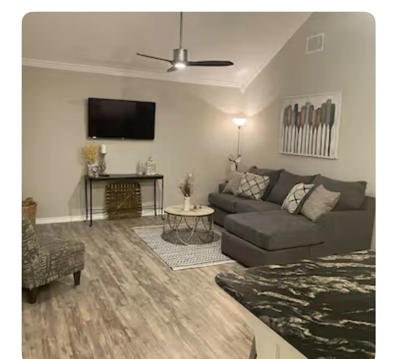 Living room featuring ceiling fan, wood-type flooring, ornamental molding, and vaulted ceiling