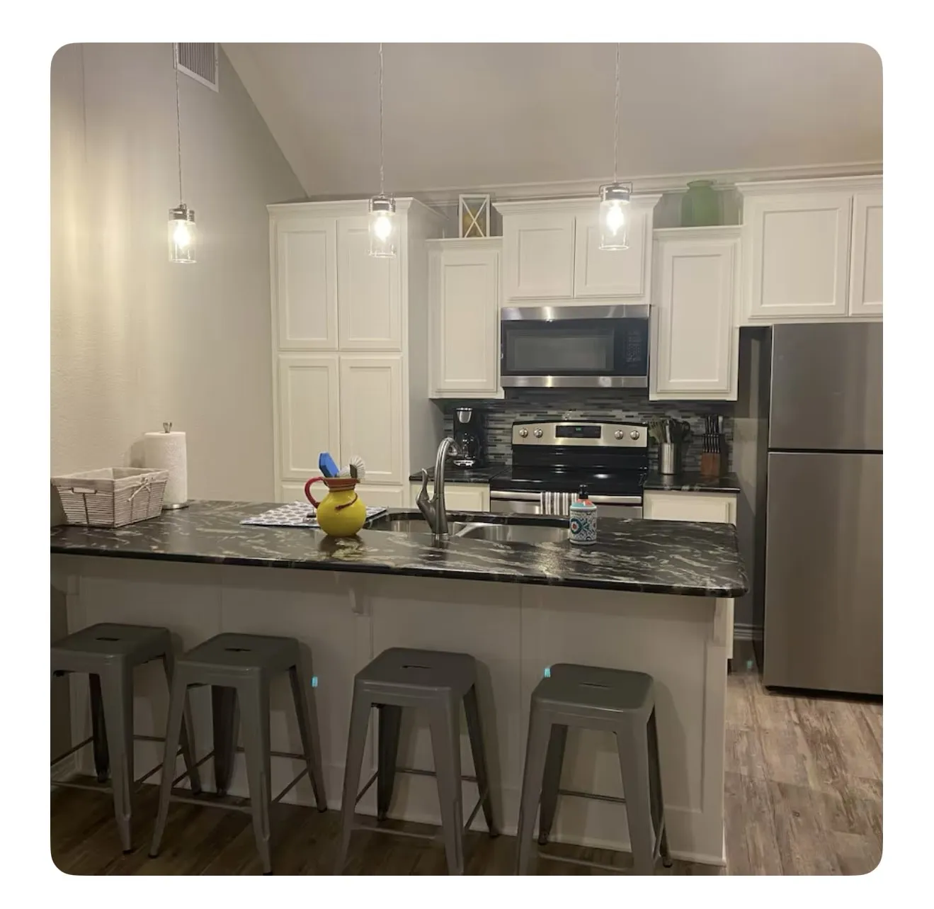 Kitchen with decorative backsplash, white cabinetry, stainless steel appliances, and wood-type flooring