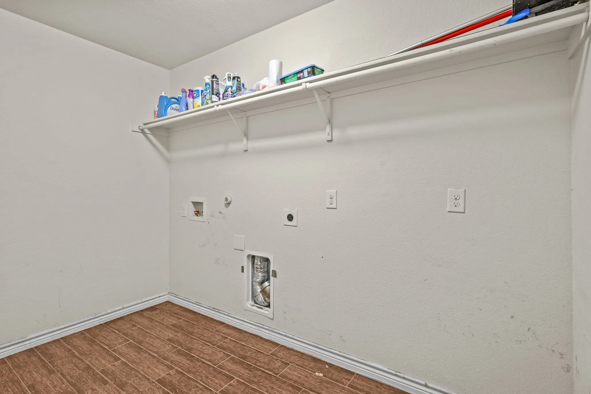 Clothes washing area with hookup for an electric dryer, hookup for a washing machine, hookup for a gas dryer, and dark wood-type flooring