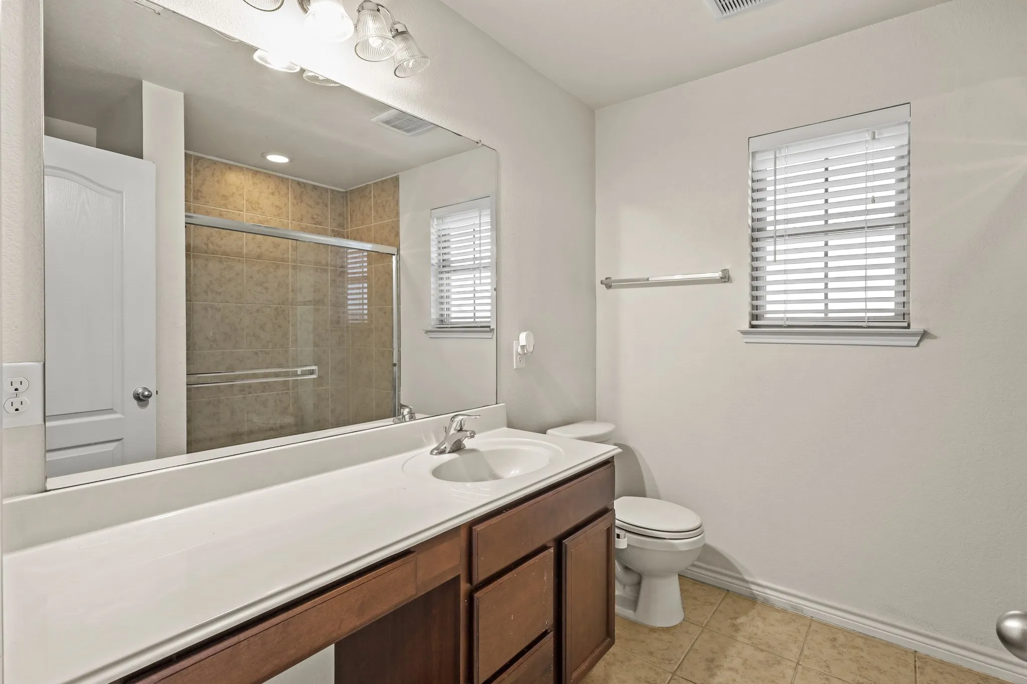 Bathroom featuring tile patterned floors, vanity, a shower with shower door, and toilet