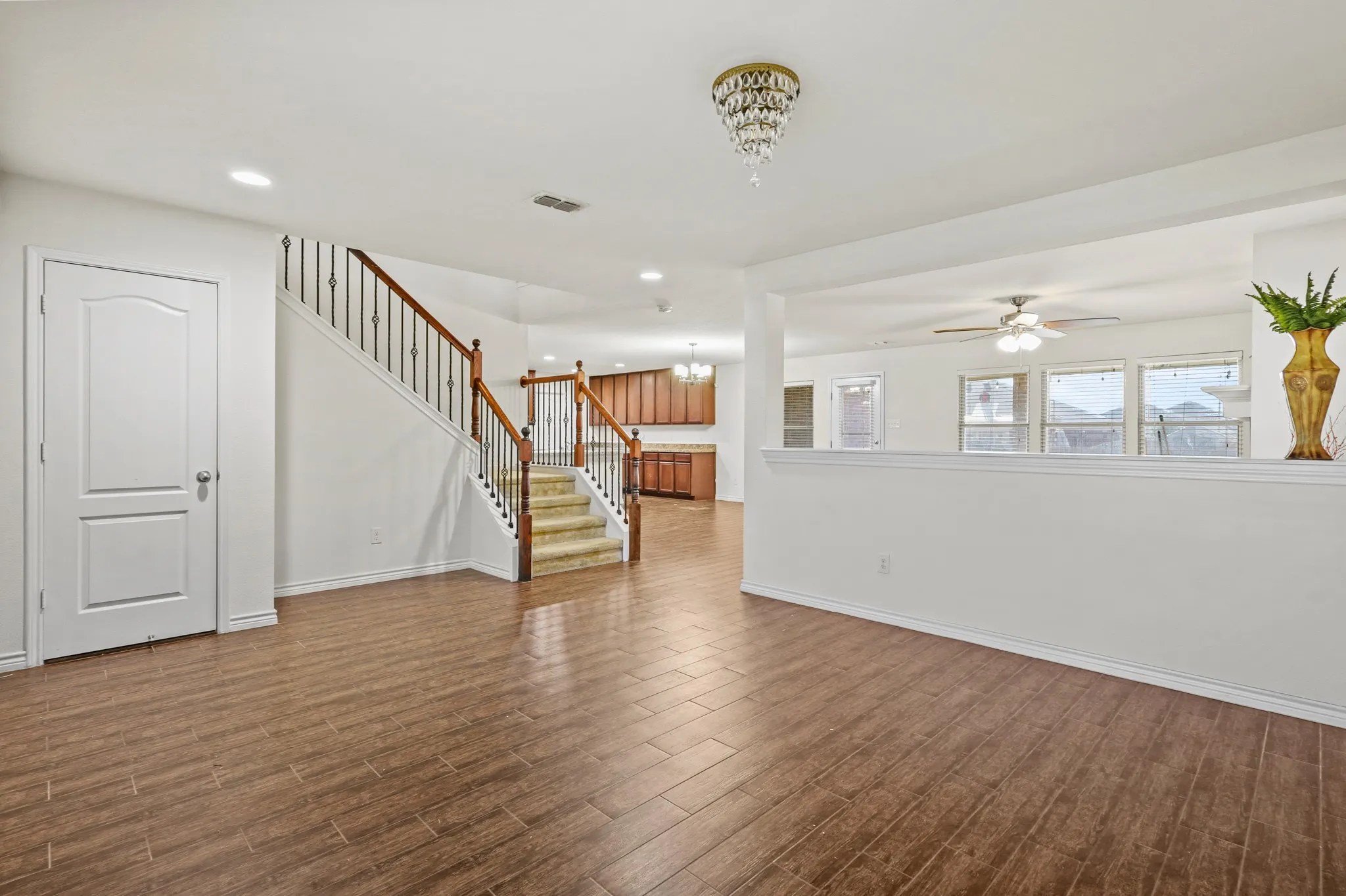 Unfurnished living room with ceiling fan with notable chandelier and dark wood-type flooring