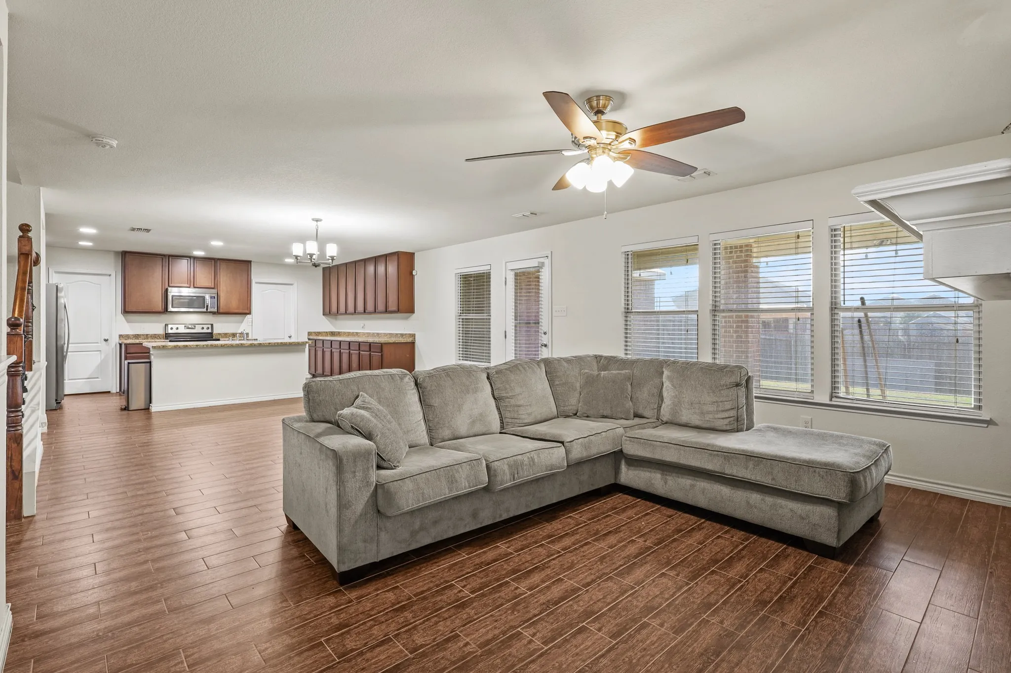 Living room with ceiling fan with notable chandelier and dark hardwood / wood-style floors