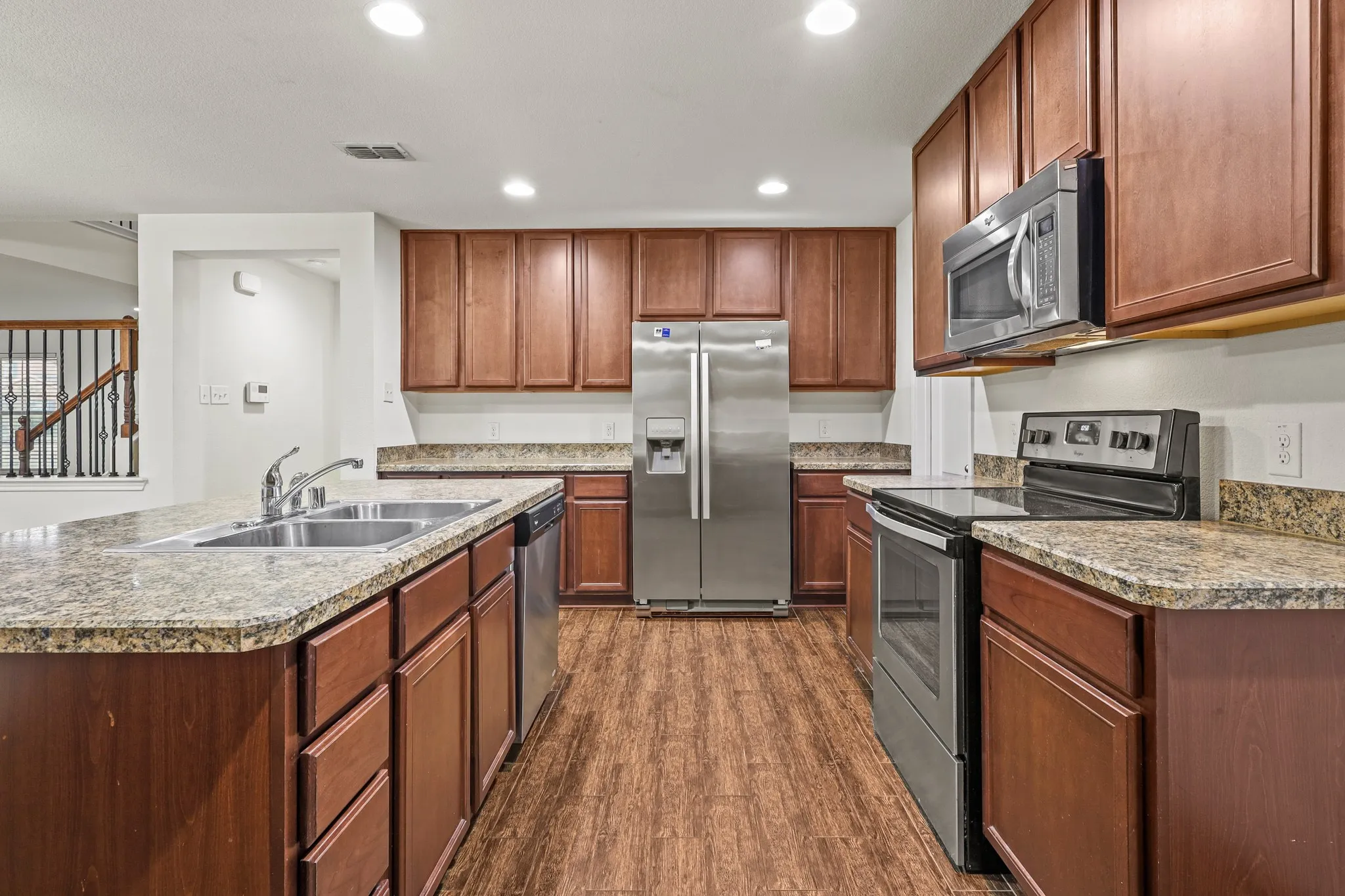 Kitchen featuring wood-type flooring, appliances with stainless steel finishes, a center island with sink, and sink