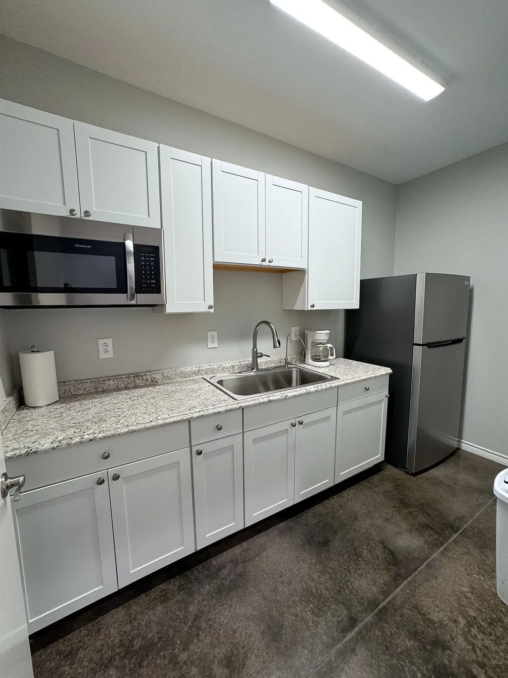 Break room kitchen with white cabinetry, sink, and appliances with stainless steel finishes