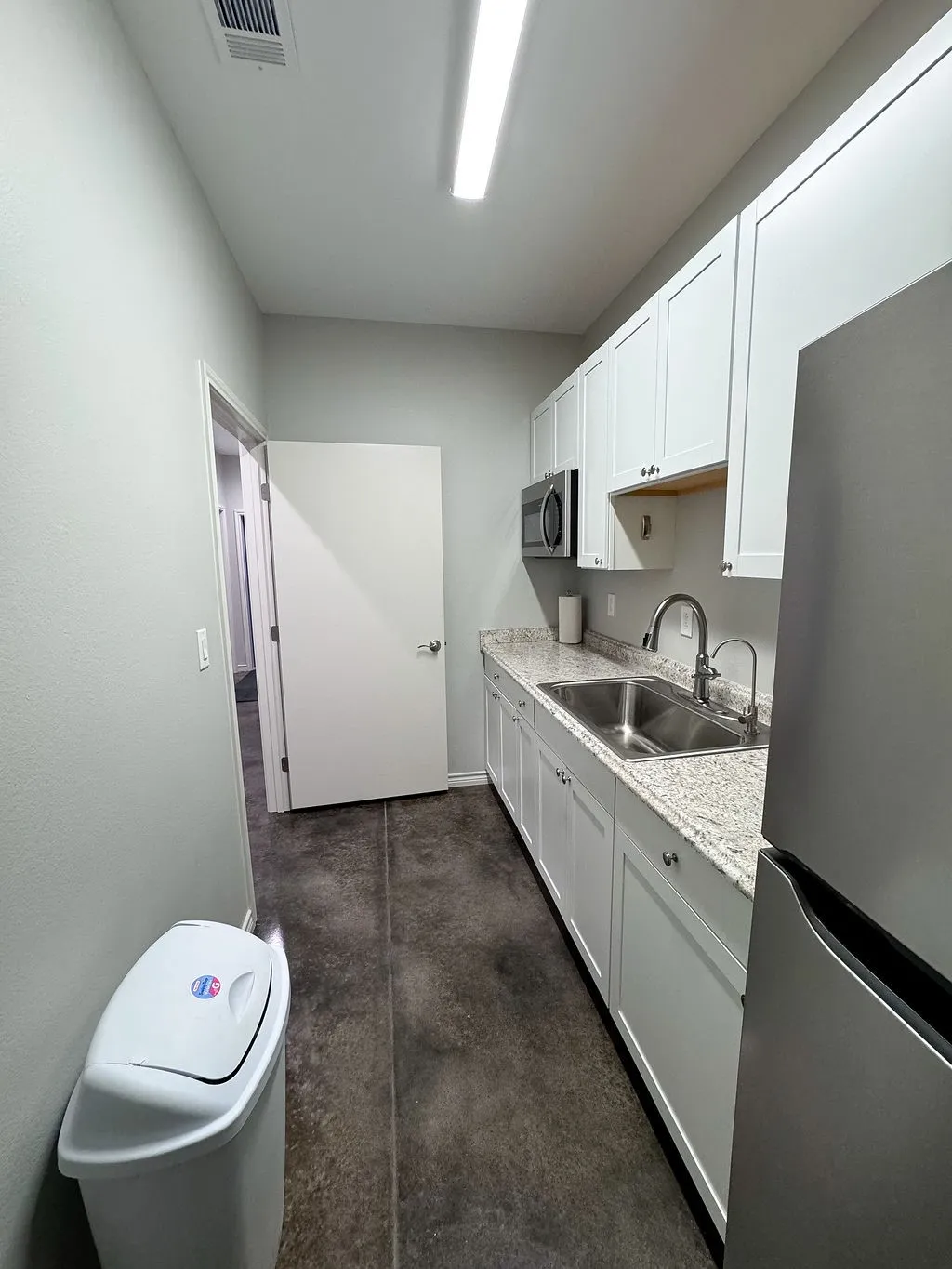 Kitchen with light stone counters, stainless steel appliances, white cabinetry, and sink