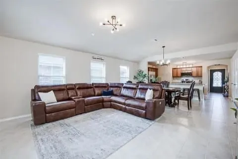 Living room with a healthy amount of sunlight, lofted ceiling, and a notable chandelier
