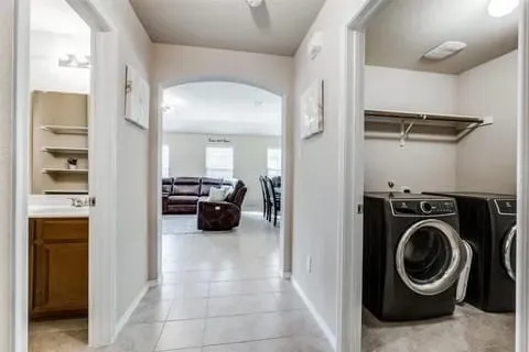 Laundry room featuring washing machine and clothes dryer, ceiling fan, and light tile patterned floors