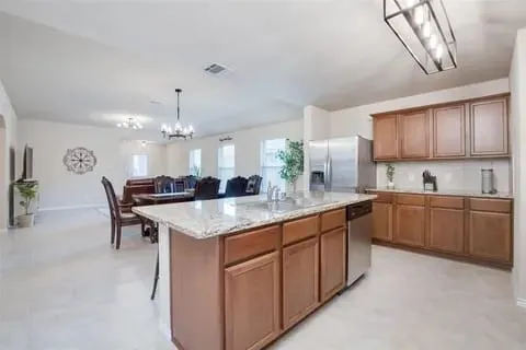 Kitchen with a center island, a kitchen breakfast bar, a chandelier, pendant lighting, and appliances with stainless steel finishes