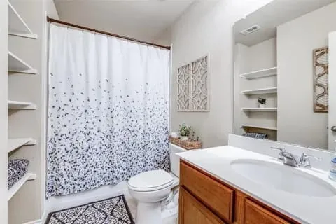 Bathroom with a shower with curtain, vanity, and toilet