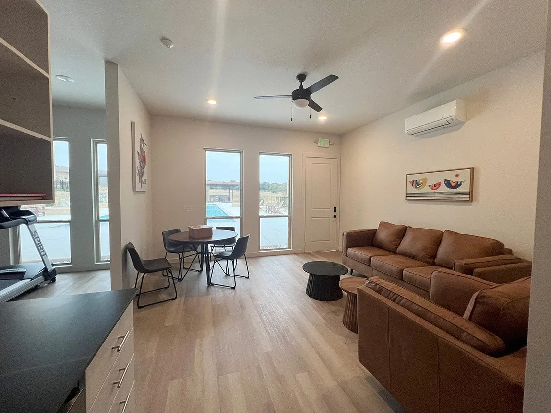 Living room with a wall mounted air conditioner, light wood-type flooring, and ceiling fan