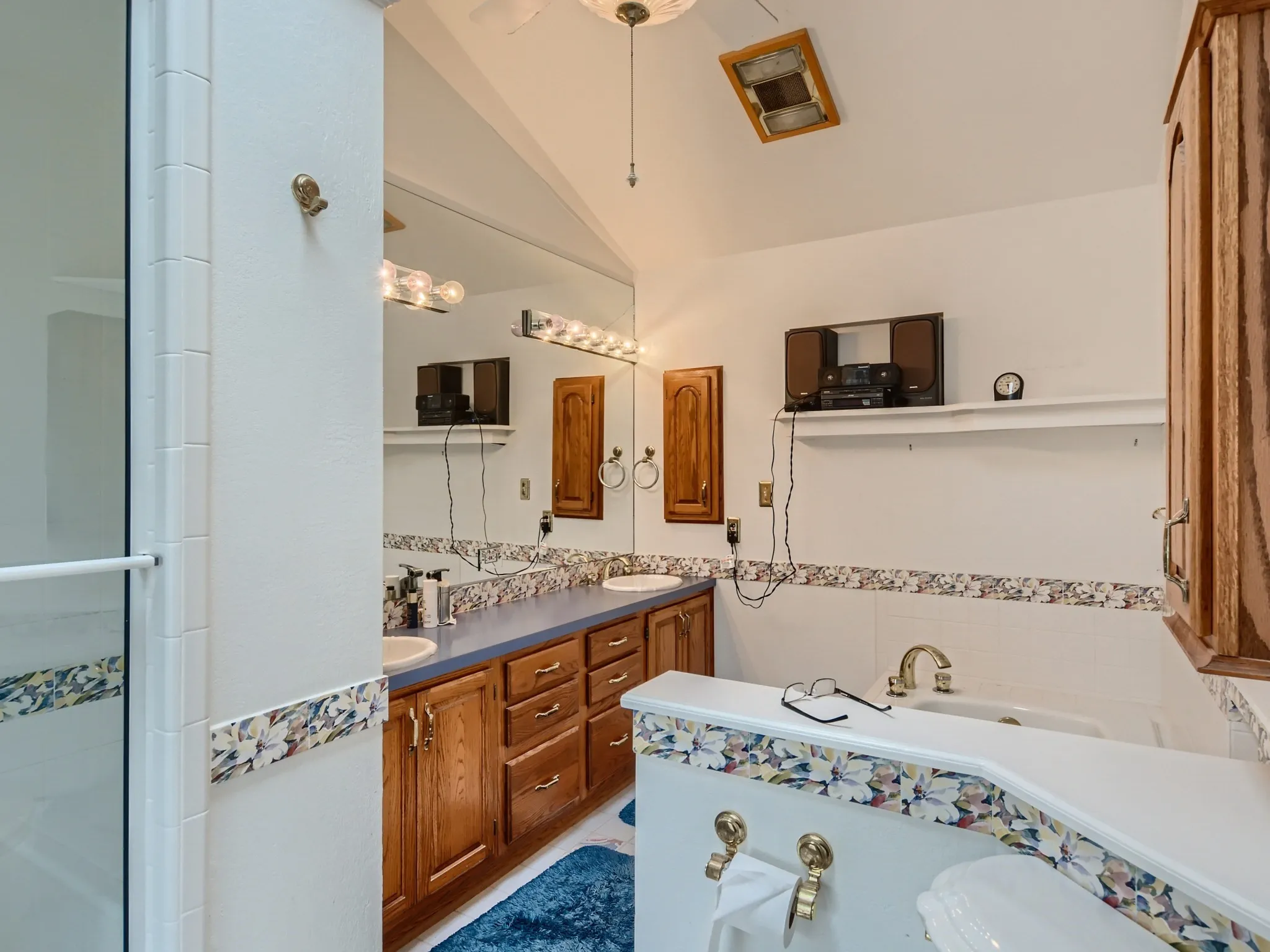 Bathroom with vanity, lofted ceiling, and plus walk in shower