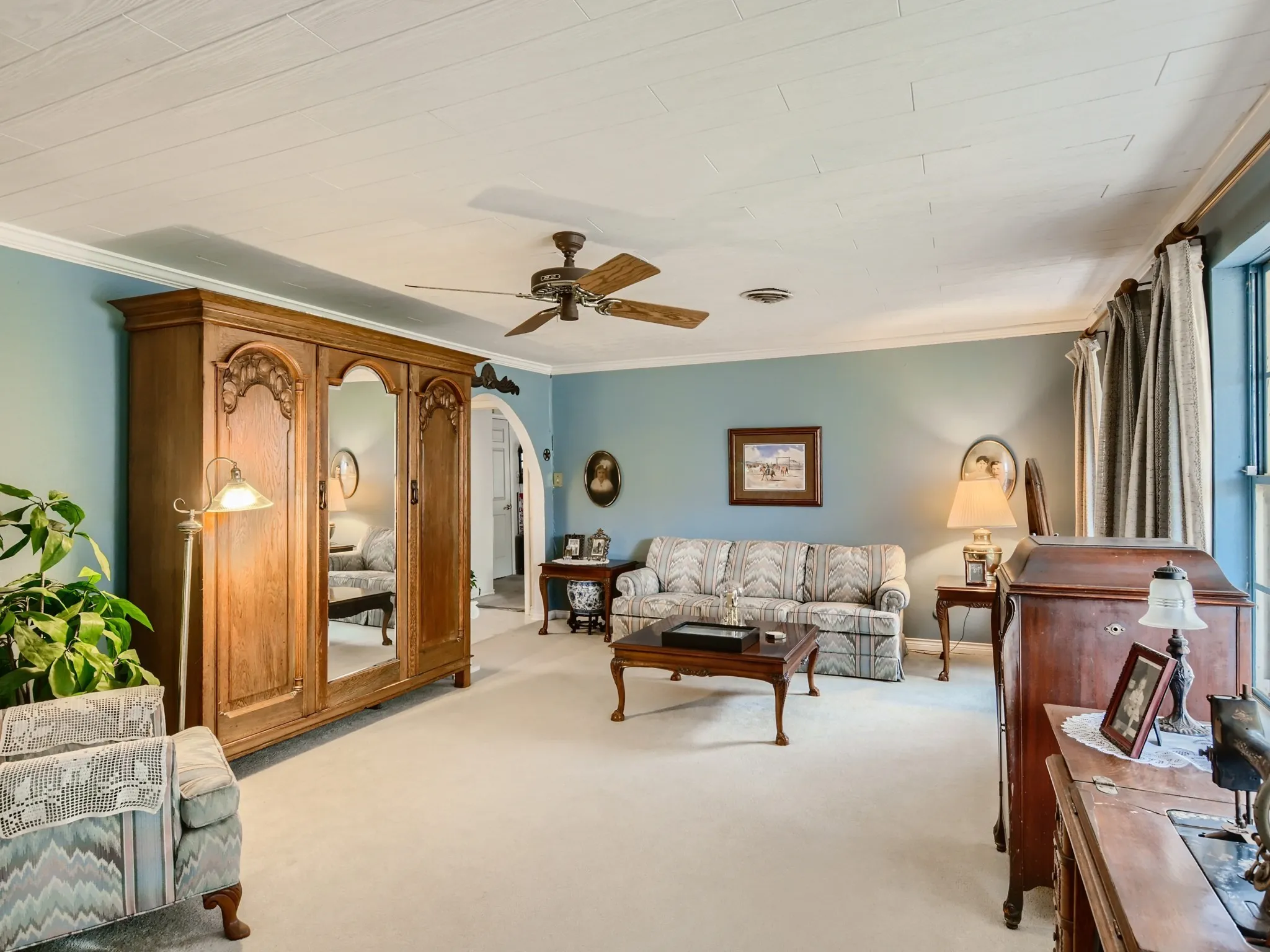 Living room featuring light carpet, ceiling fan, and ornamental molding
