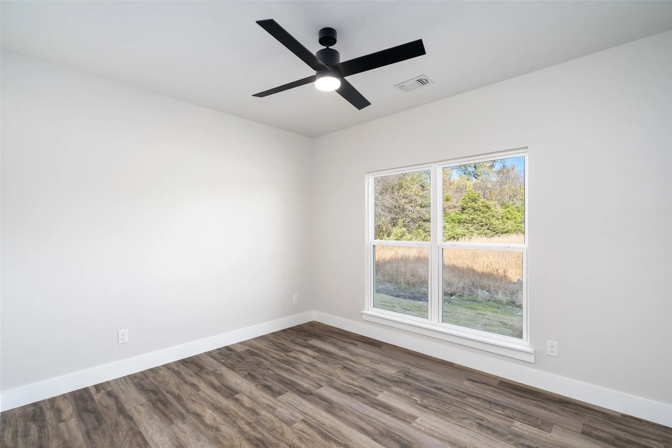 Empty room with wood-type flooring and ceiling fan
