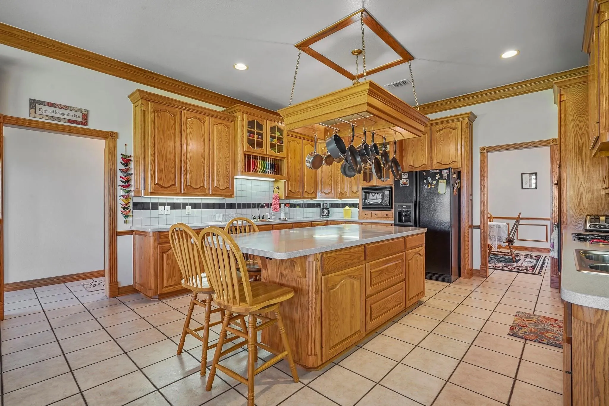 Kitchen featuring decorative backsplash, ornamental molding, sink, black appliances, and a kitchen island