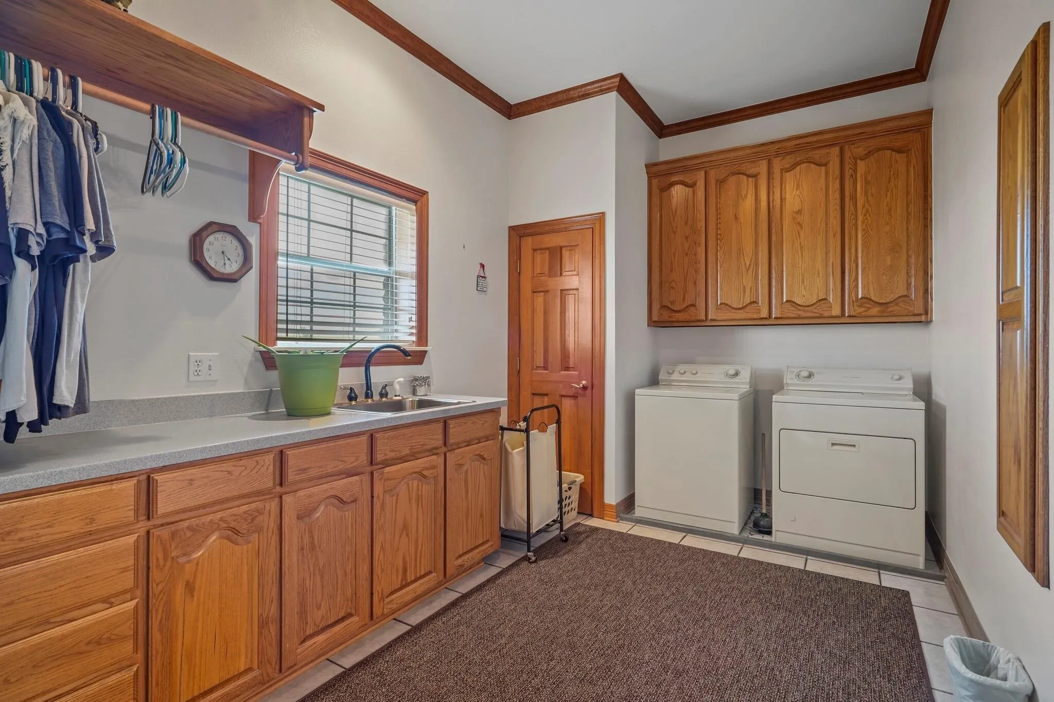 Washroom with cabinets, crown molding, sink, independent washer and dryer, and light tile patterned flooring