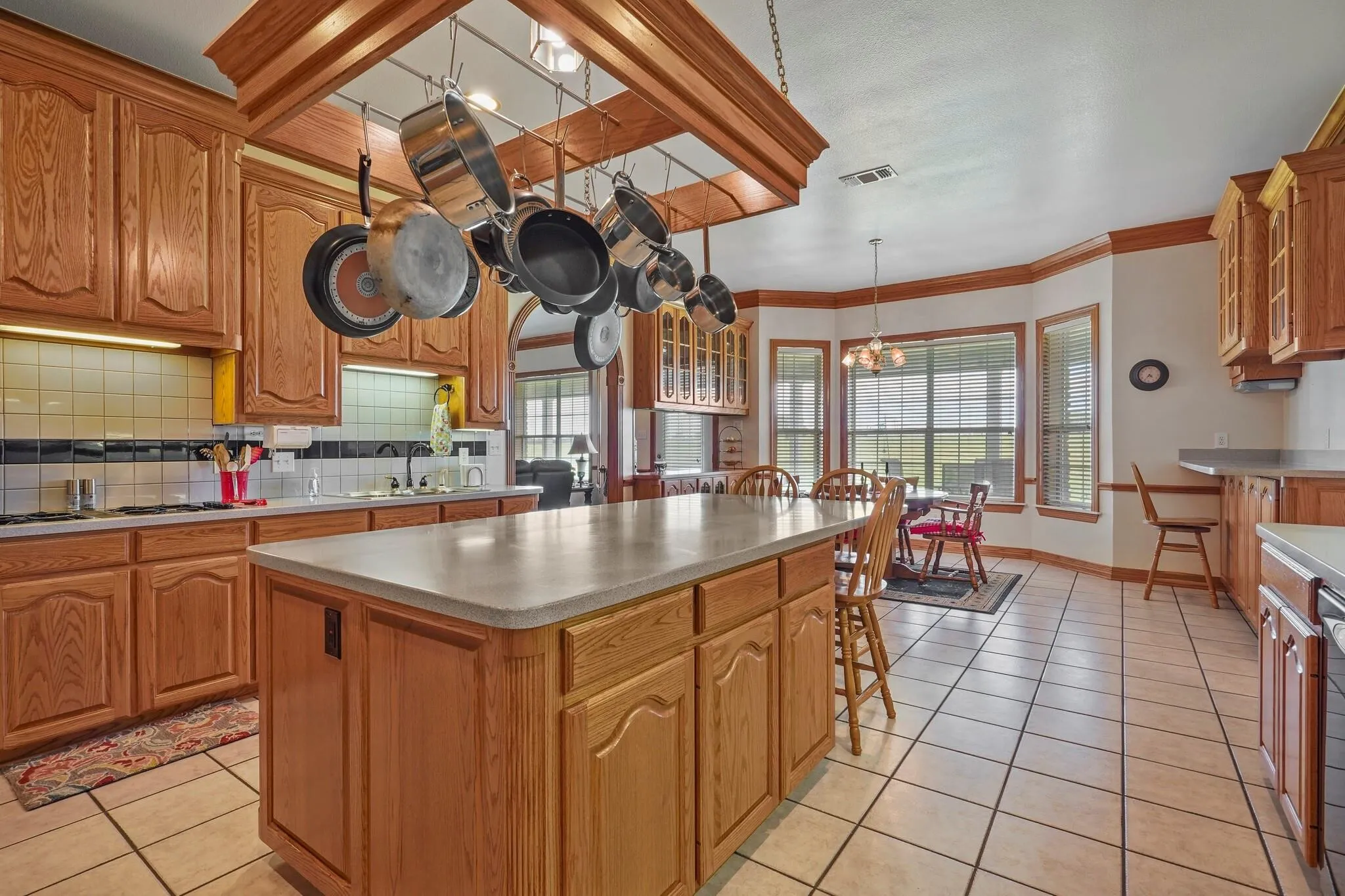 Kitchen with decorative light fixtures, a center island, decorative backsplash, and light tile patterned floors