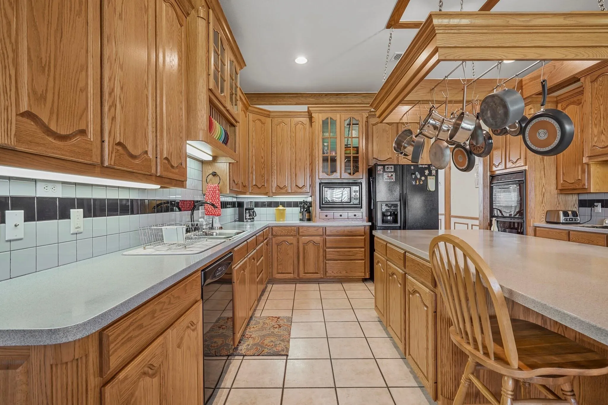 Kitchen featuring tasteful backsplash, sink, light tile patterned floors, and black appliances