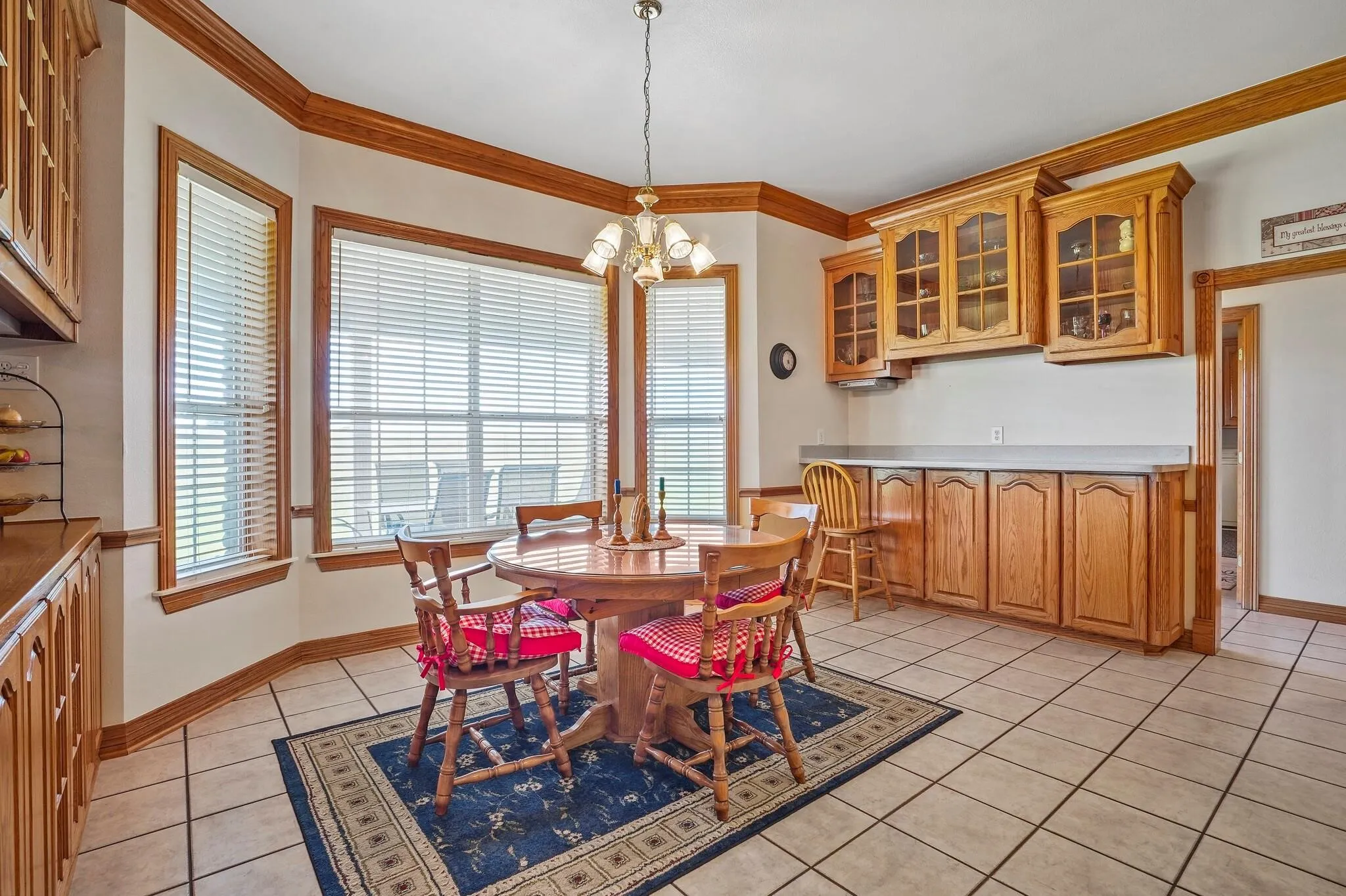 Dining area with light tile patterned flooring, crown molding, and an inviting chandelier