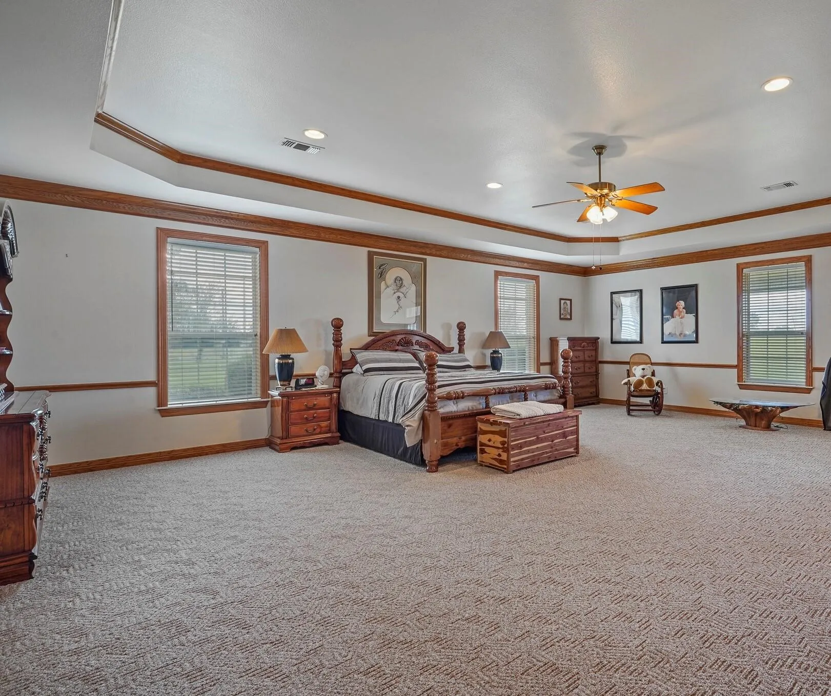 Carpeted bedroom with ceiling fan, ornamental molding, and a tray ceiling