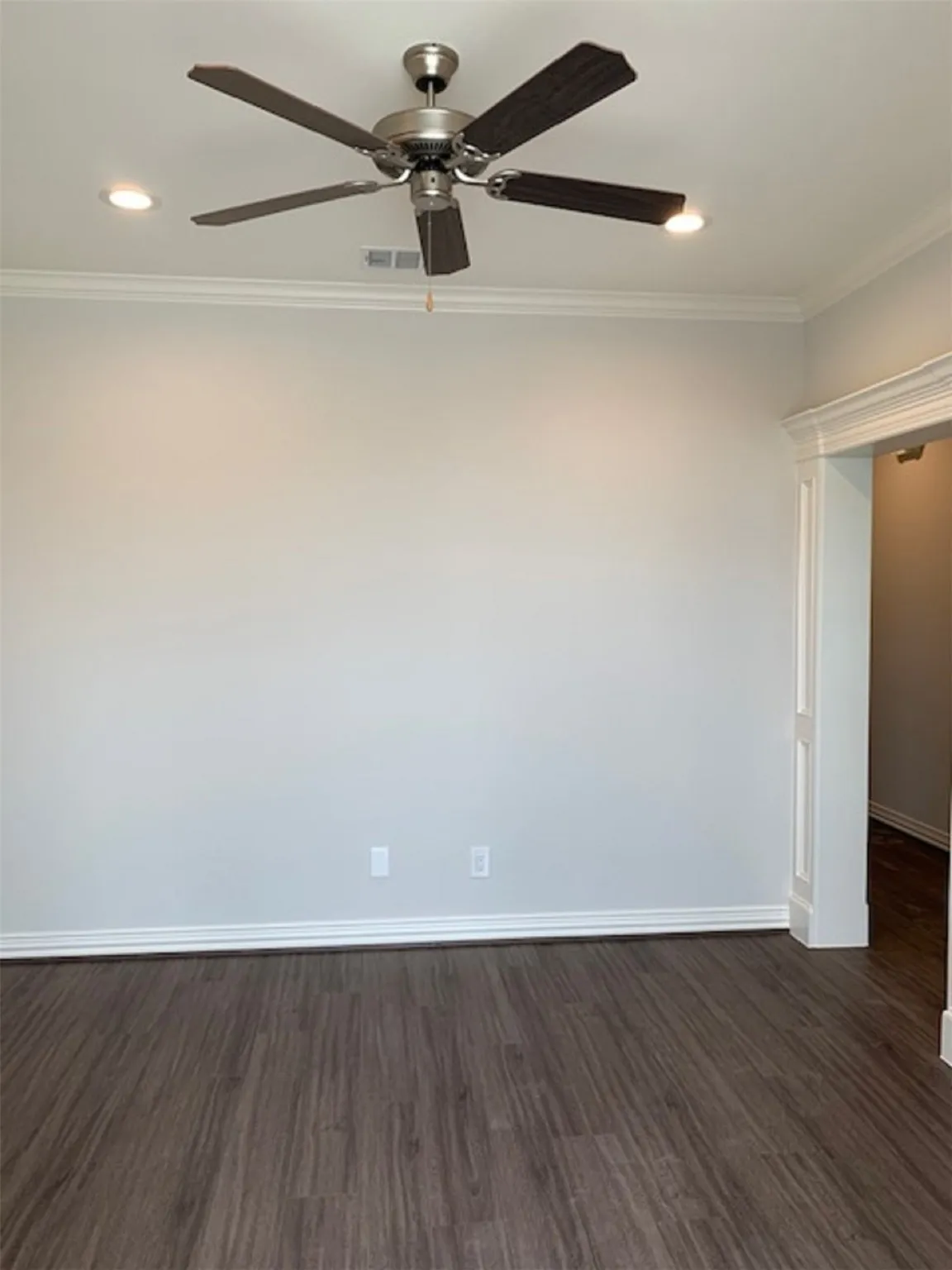 Empty room featuring ceiling fan, dark hardwood / wood-style flooring, and crown molding