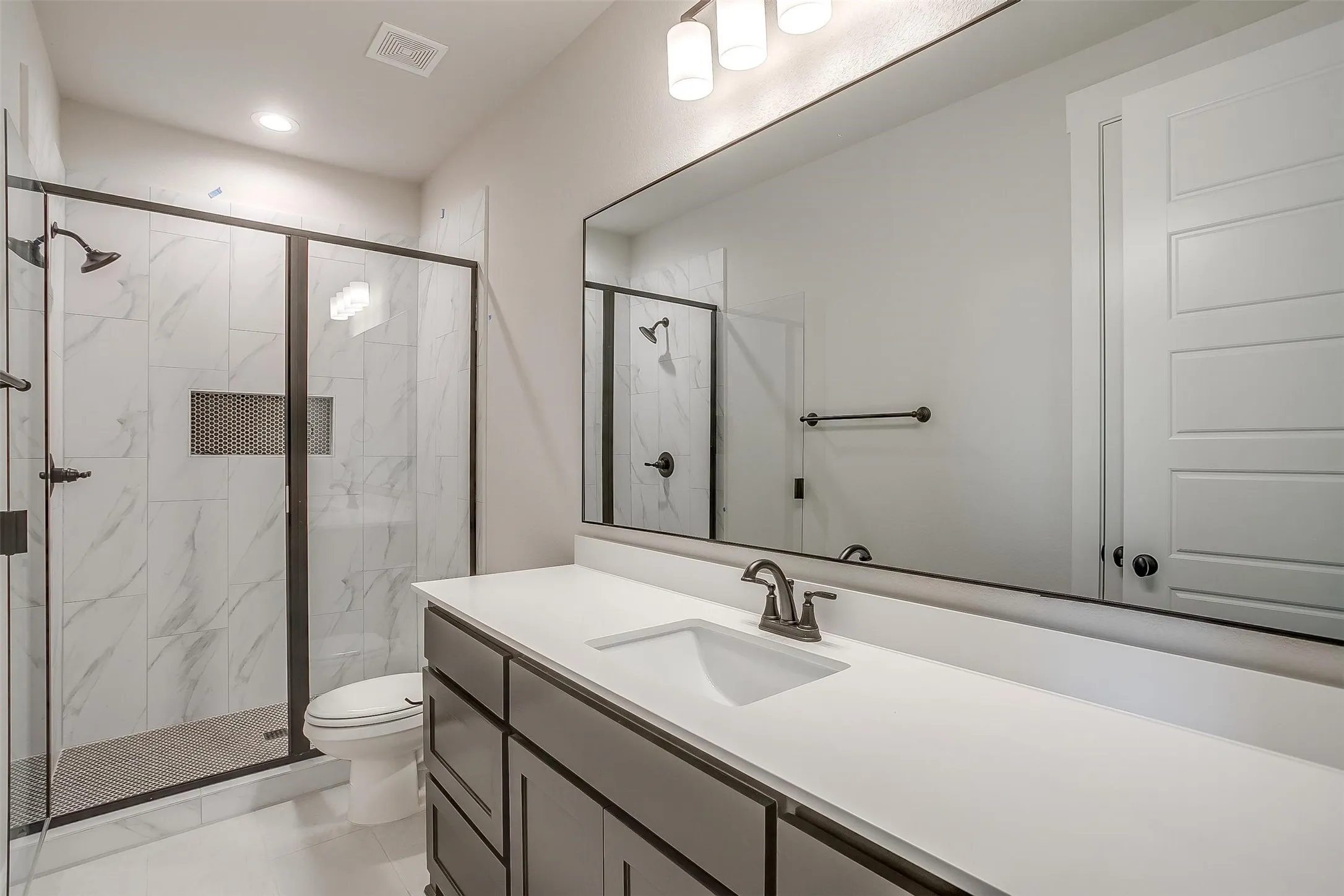 Full bath with vanity, visible vents, recessed lighting, toilet, and a marble finish shower