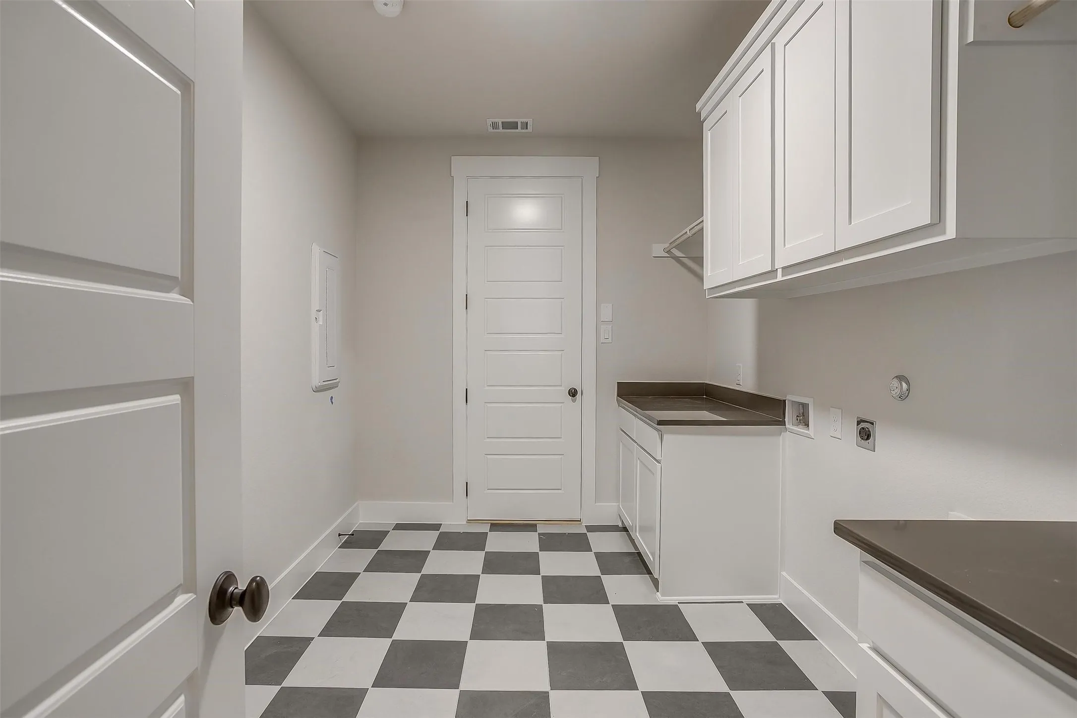Clothes washing area with dark floors, visible vents, hookup for an electric dryer, baseboards, and cabinet space