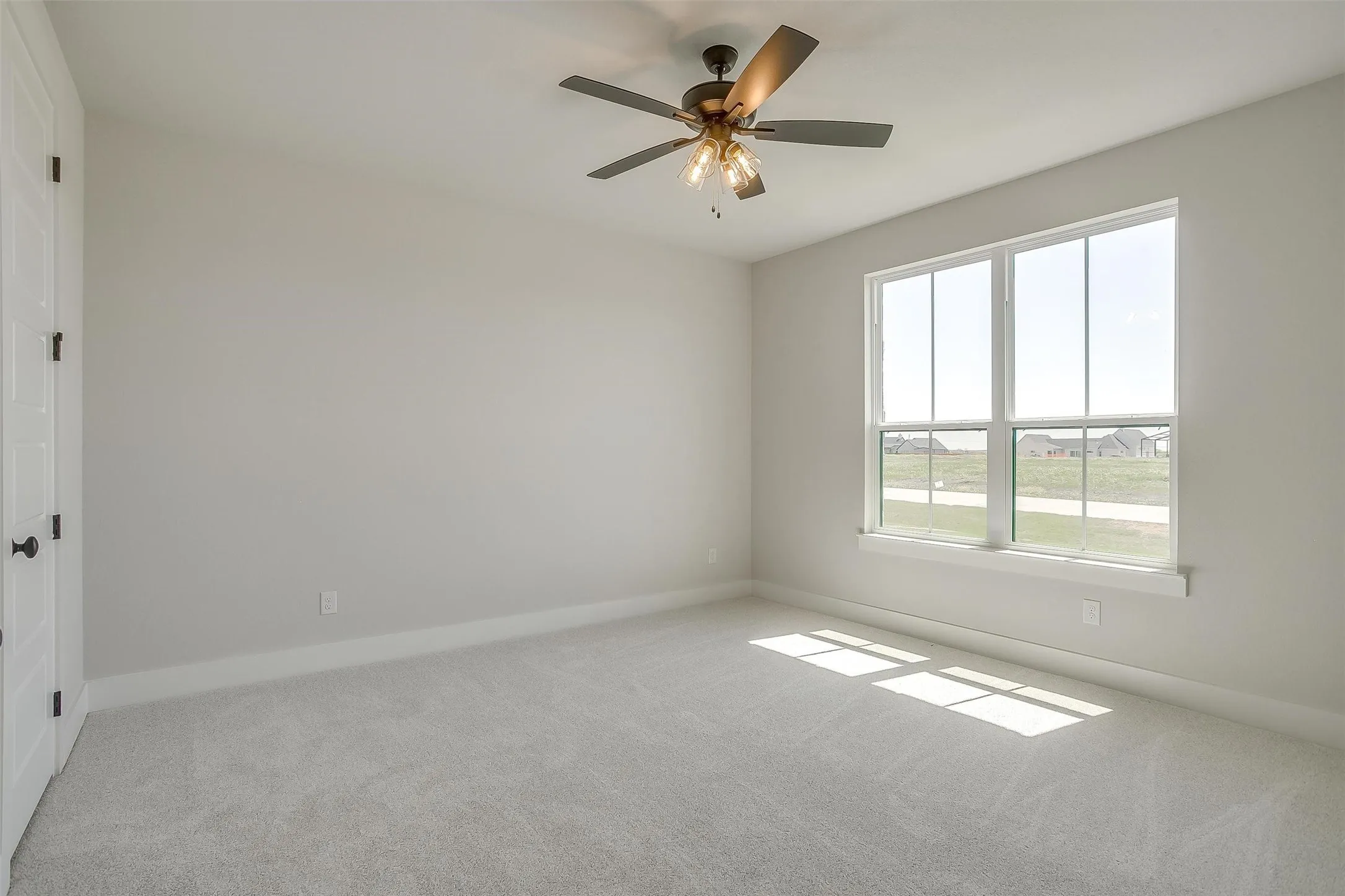 Carpeted spare room with baseboards and a ceiling fan