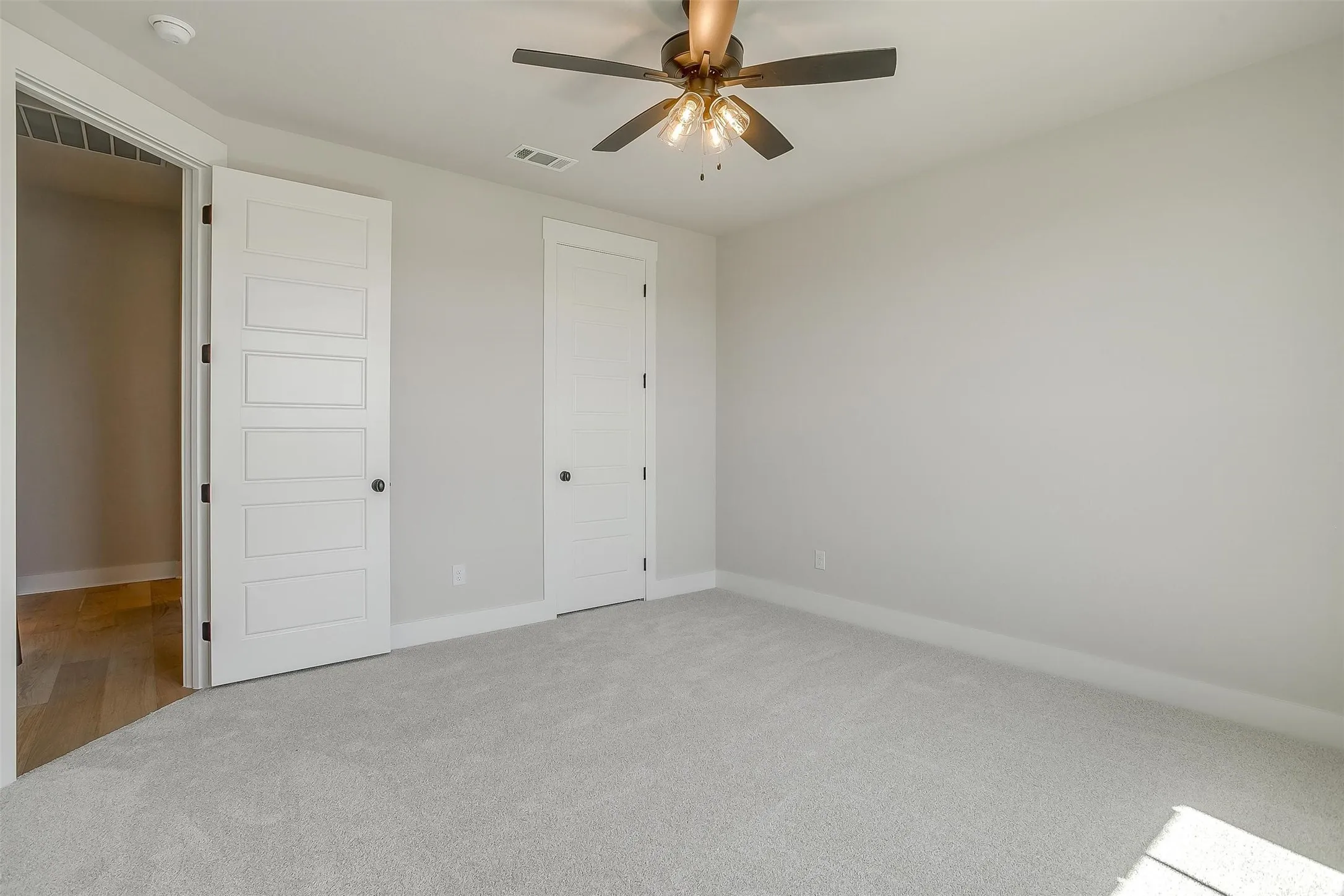 Unfurnished bedroom featuring carpet flooring, visible vents, baseboards, and ceiling fan