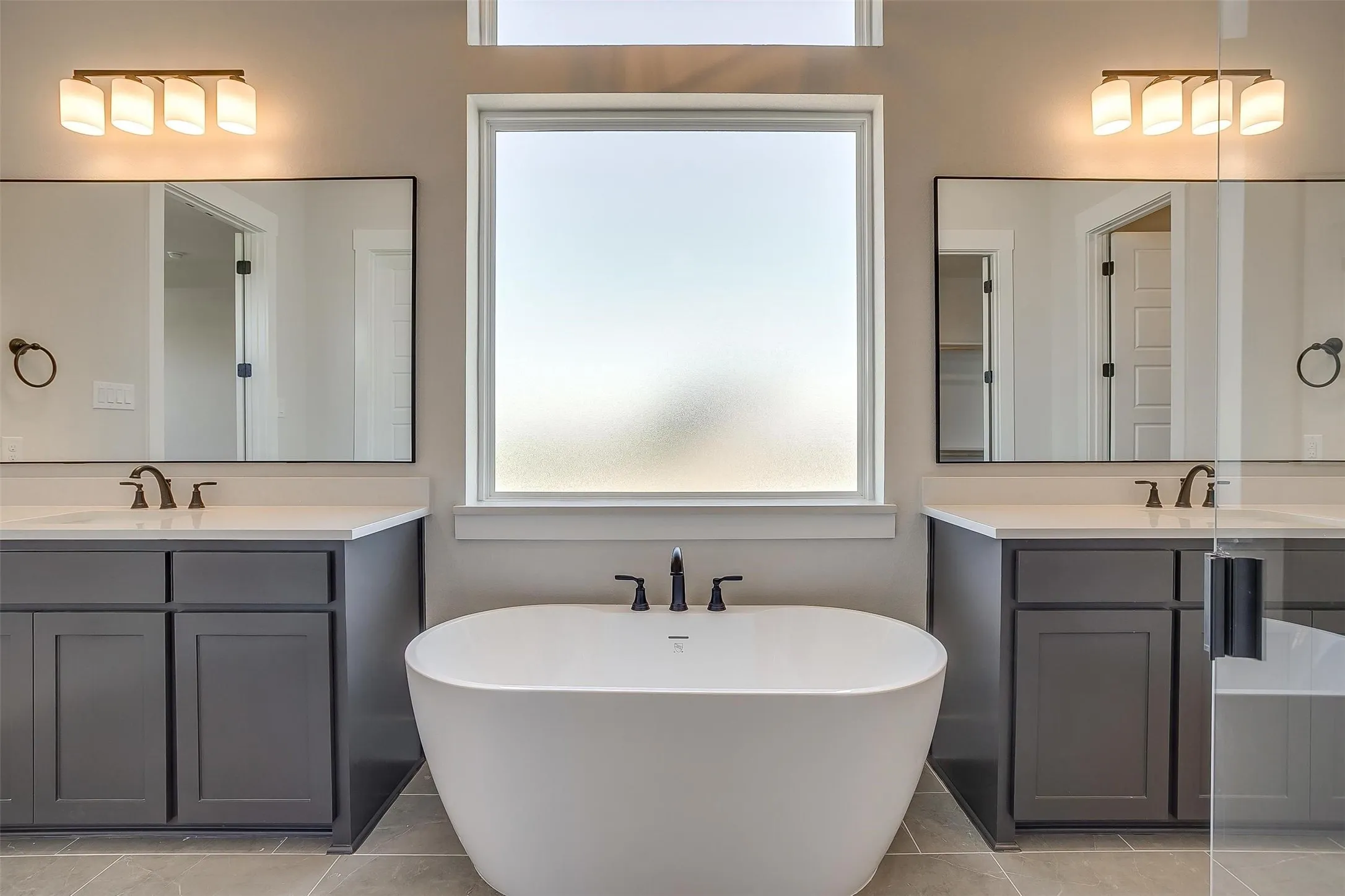 Bathroom featuring a freestanding bath, two vanities, a sink, and tile patterned flooring