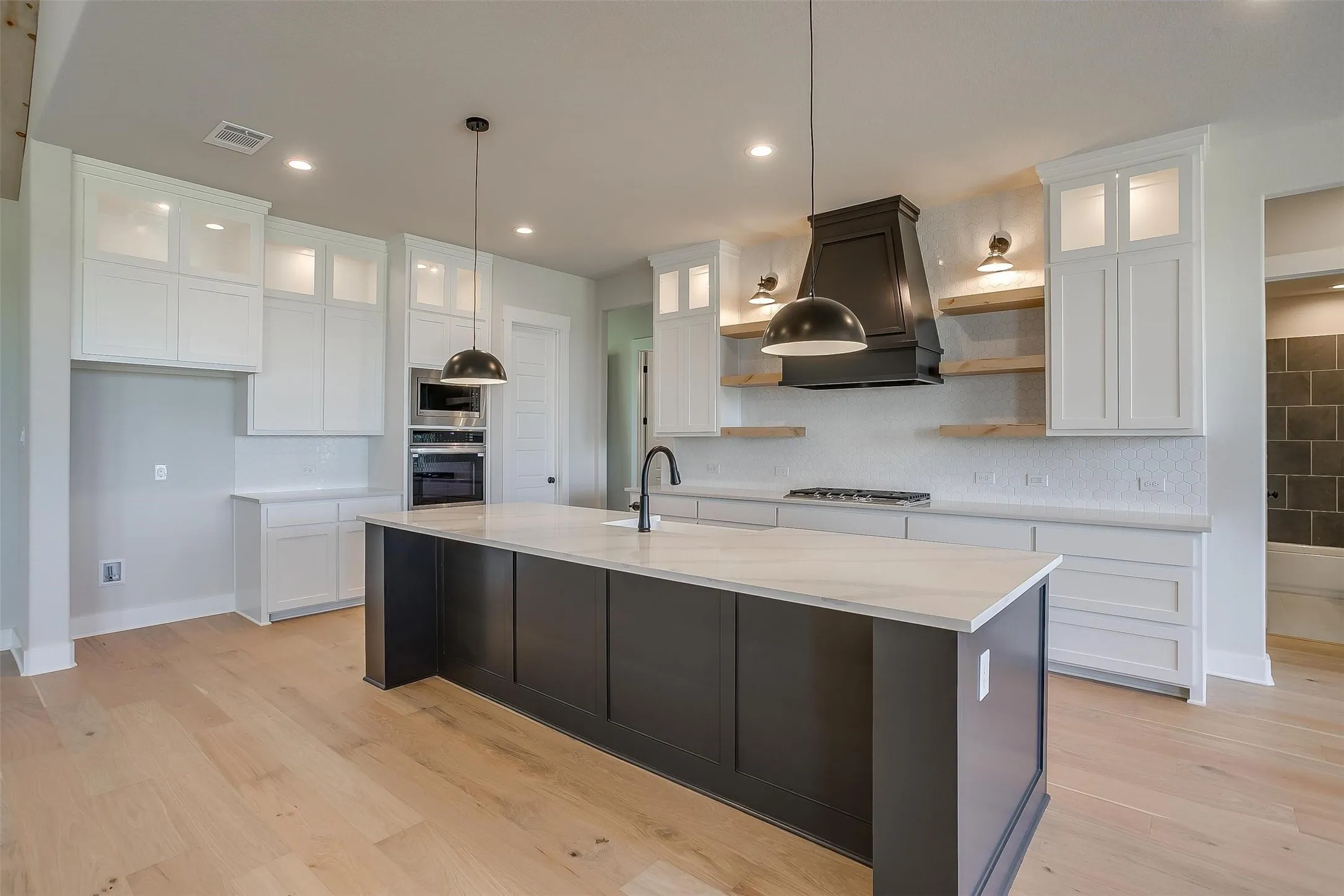Kitchen with premium range hood, open shelves, visible vents, stainless steel appliances, and a sink