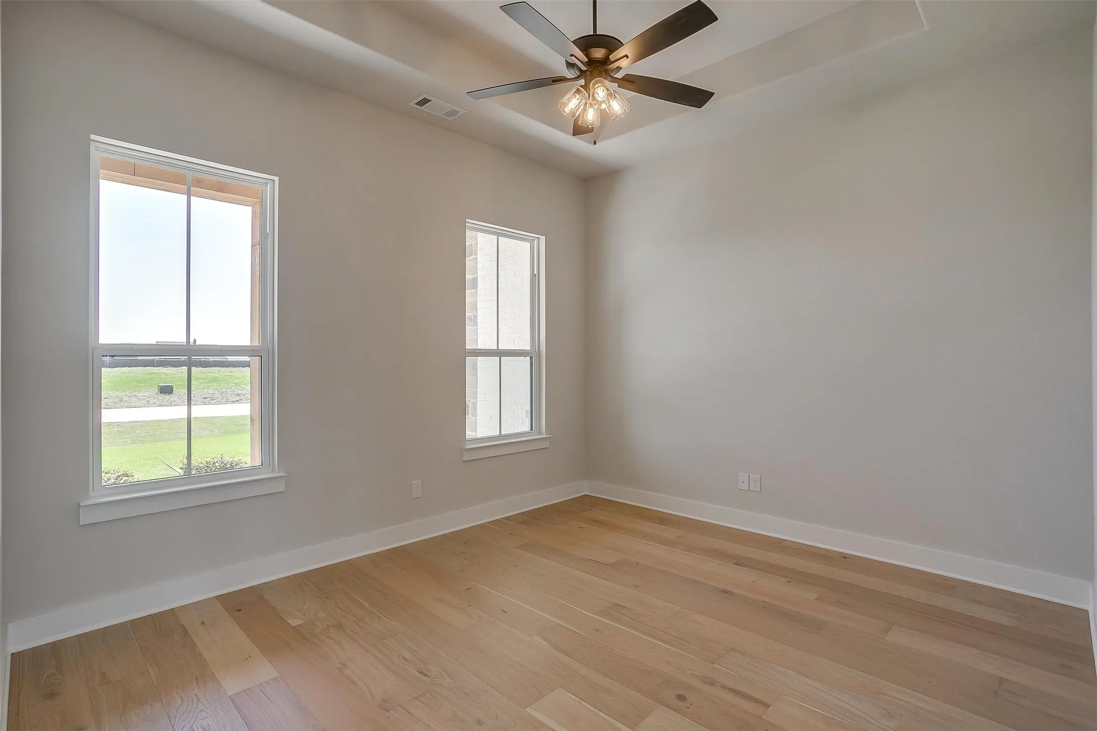 Unfurnished room with visible vents, baseboards, a raised ceiling, and light wood finished floors
