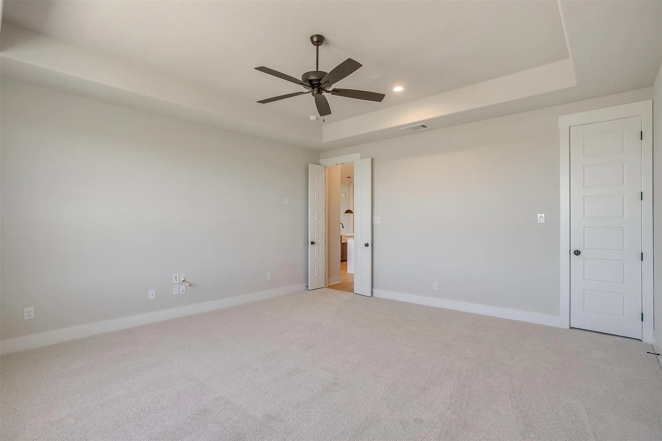 Empty room with baseboards, recessed lighting, a ceiling fan, a raised ceiling, and light colored carpet