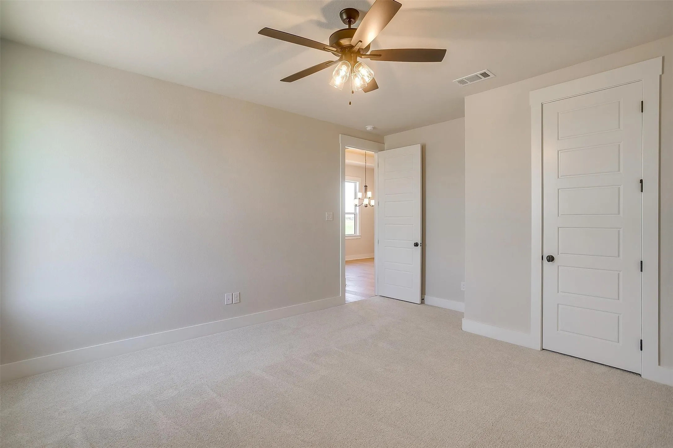 Unfurnished bedroom featuring light carpet, ceiling fan, baseboards, and visible vents