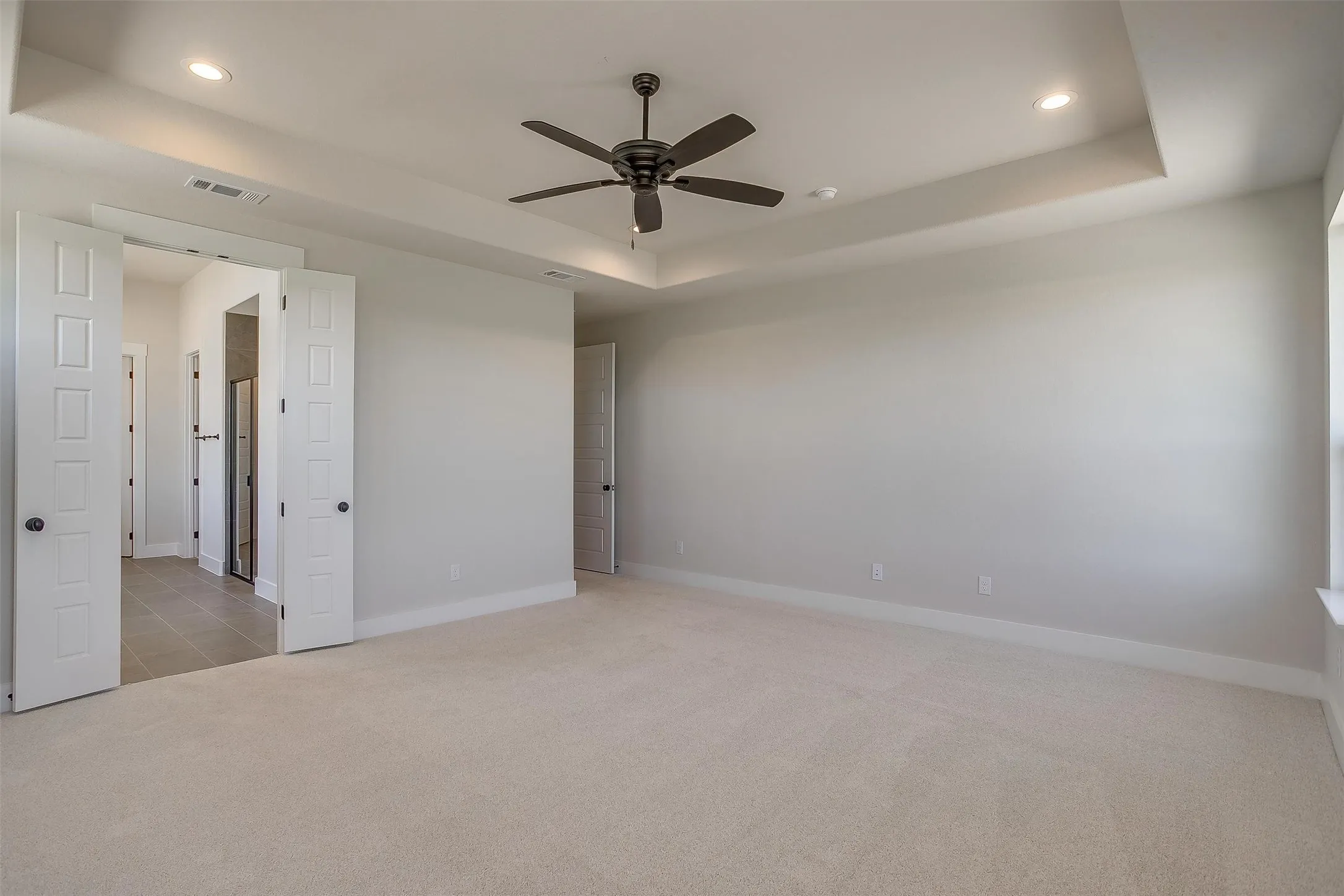 Spare room featuring visible vents, ceiling fan, carpet, a tray ceiling, and recessed lighting