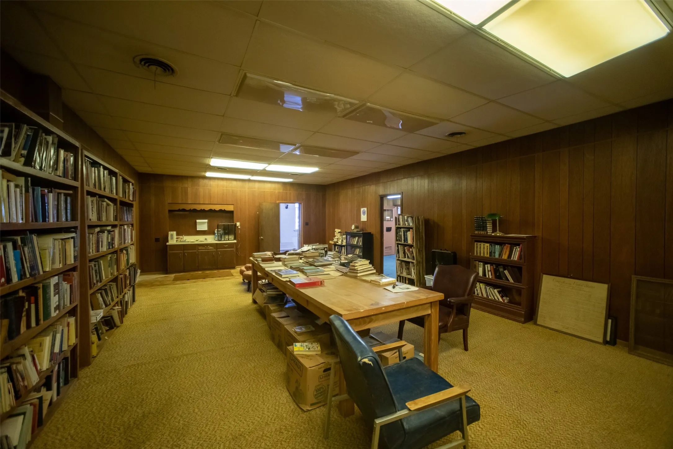Carpeted office with a paneled ceiling and built in features