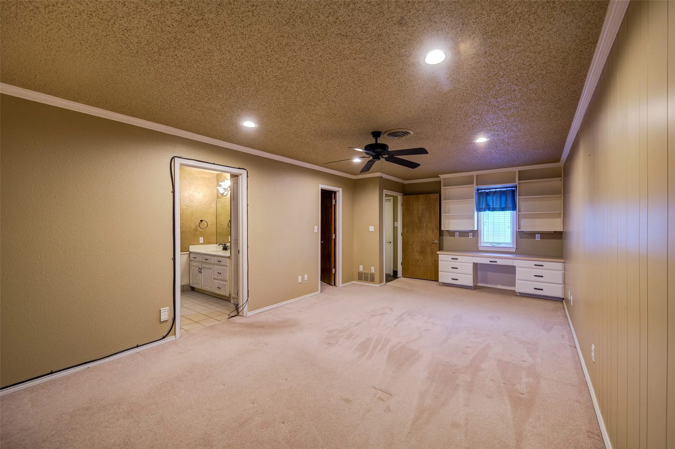 Unfurnished bedroom featuring ornamental molding, built in study area, recessed lighting, light colored carpet, and a textured ceiling