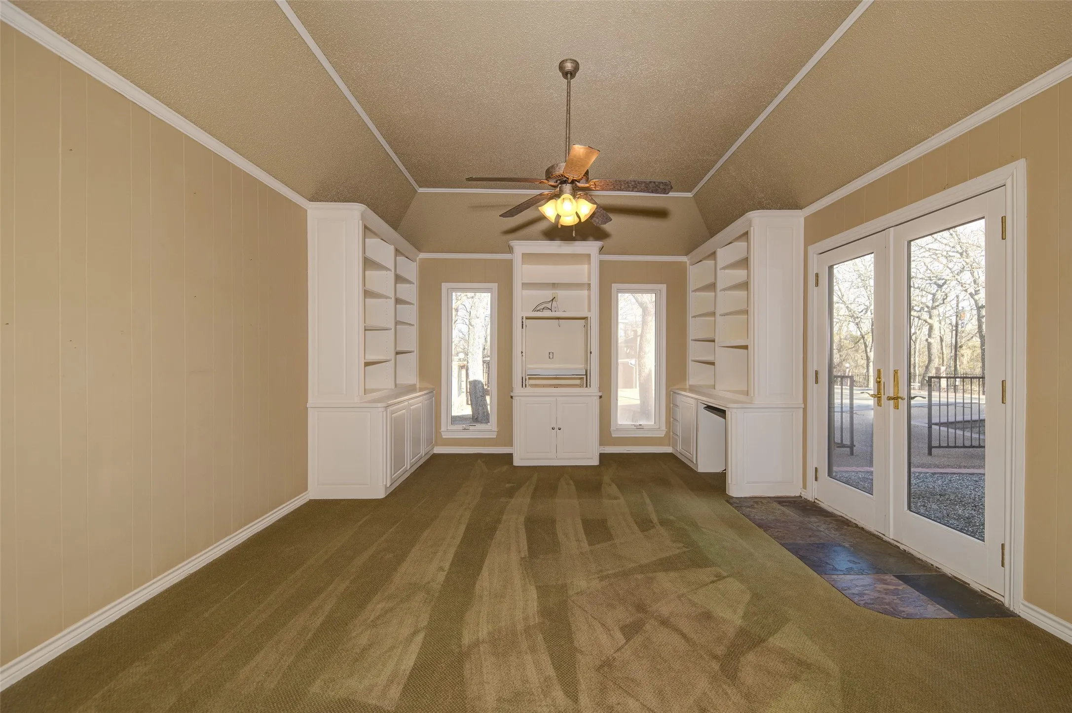 Entrance foyer with french doors, dark colored carpet, a ceiling fan, a textured ceiling, and ornamental molding