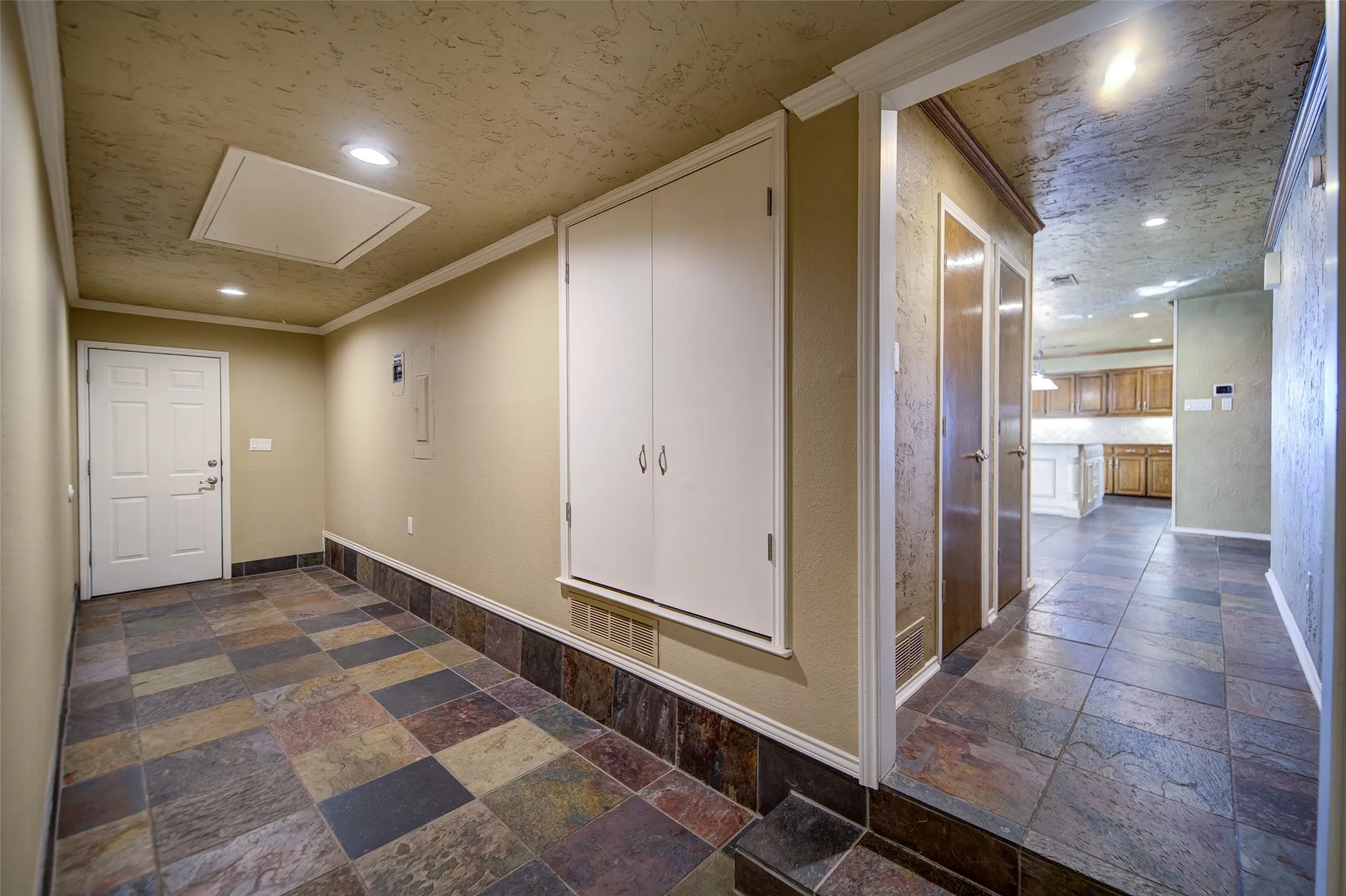 Hall featuring attic access, stone tile floors, ornamental molding, and recessed lighting