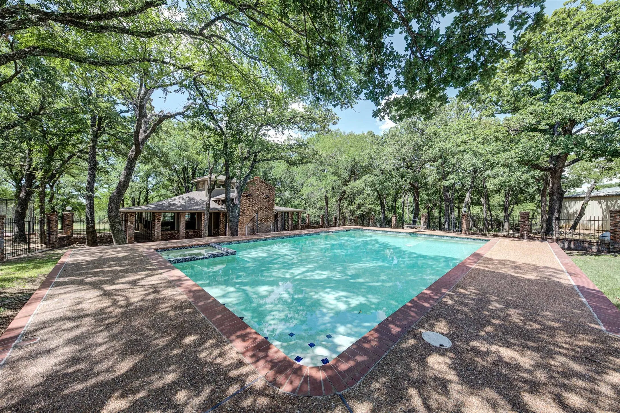 View of swimming pool featuring a pool with connected hot tub, a patio, and view of scattered trees