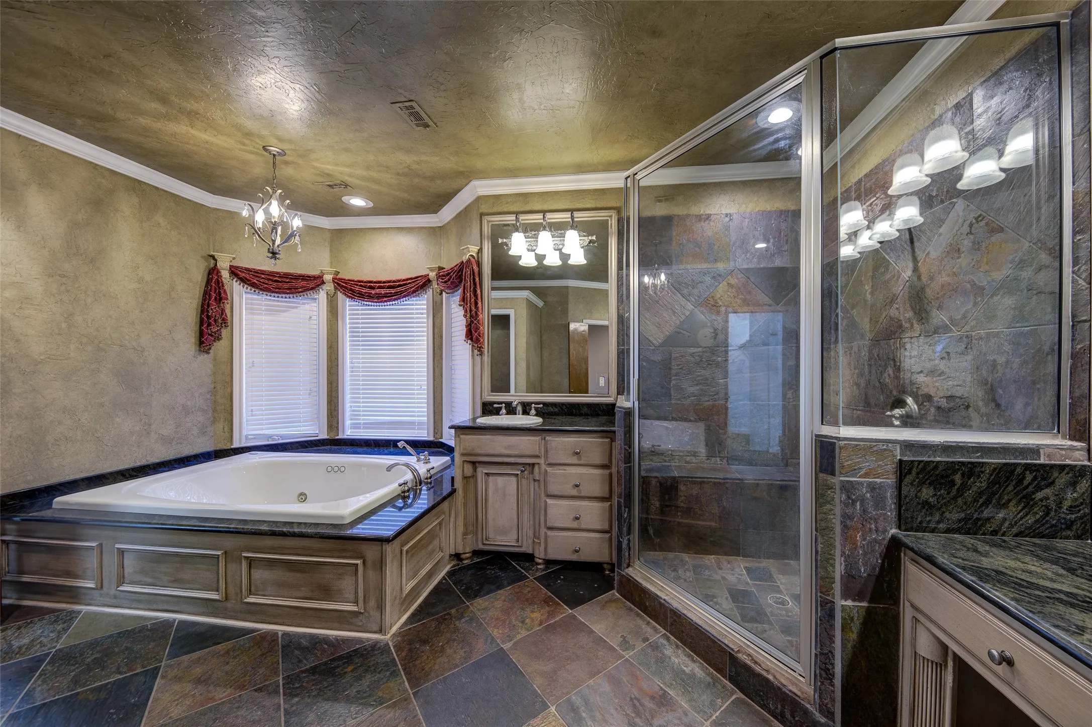 Full bathroom with vanity, a whirlpool tub, a chandelier, a shower stall, and ornamental molding