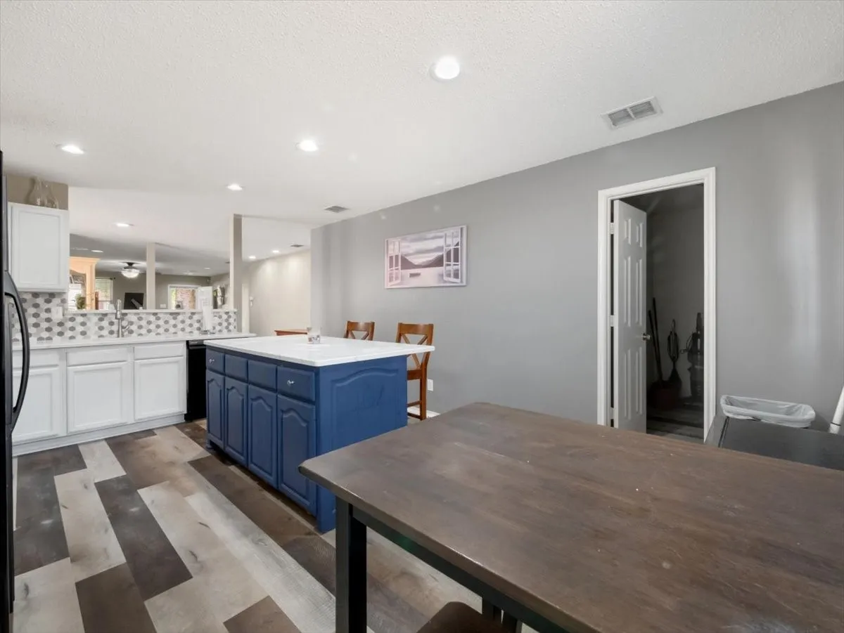 Kitchen featuring a center island, kitchen peninsula, a kitchen bar, white cabinets, and blue cabinets