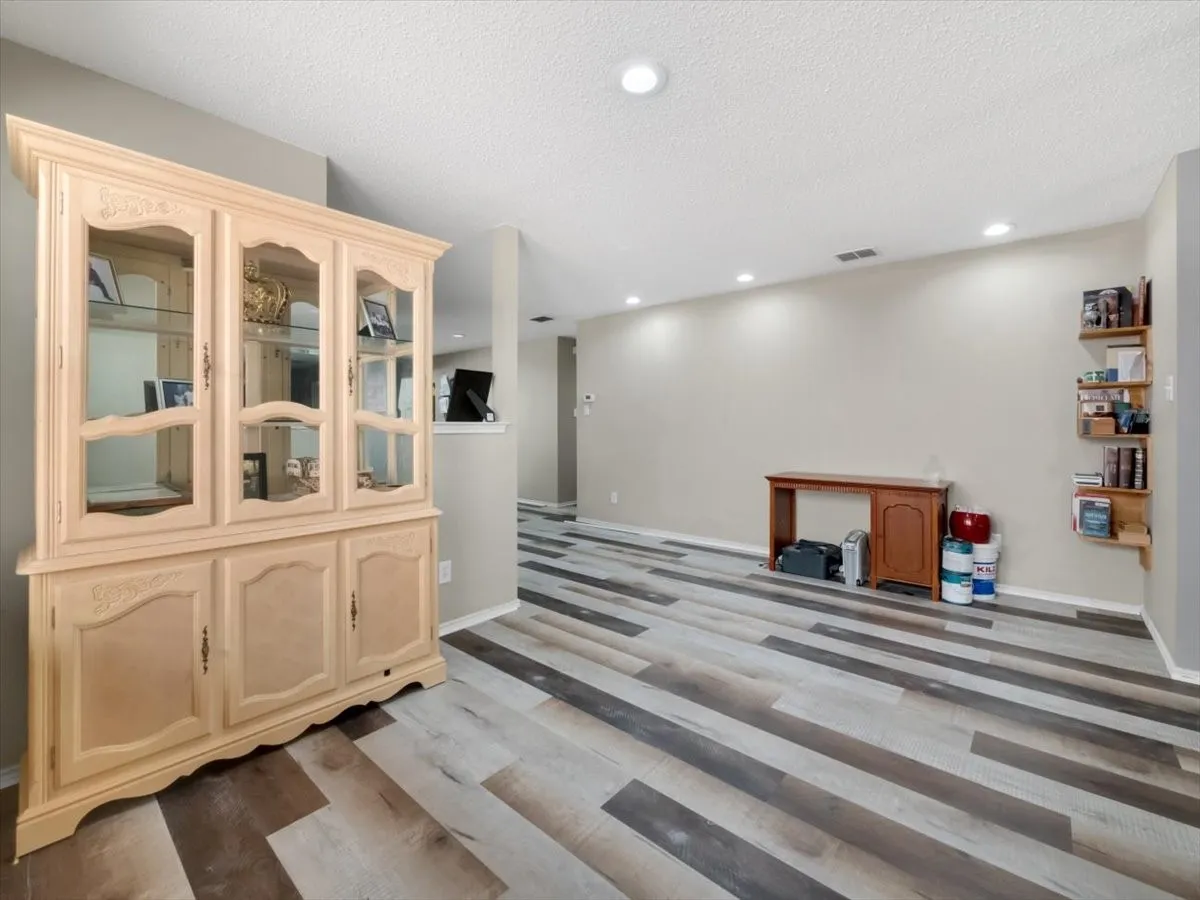 Bar featuring light brown cabinets, a textured ceiling, and hardwood / wood-style flooring