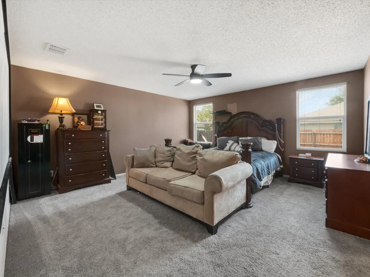 Bedroom with a textured ceiling, ceiling fan, and carpet floors