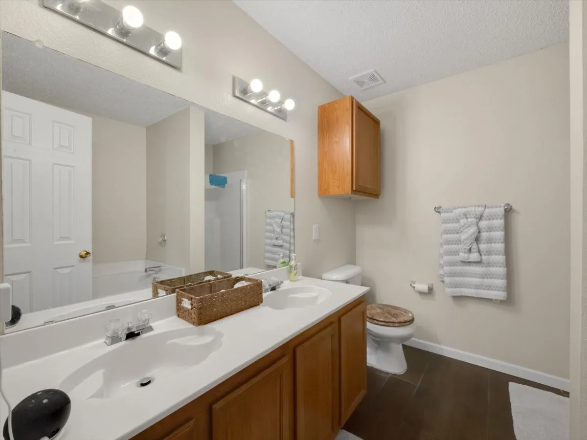 Full bathroom featuring a textured ceiling, toilet, vanity, and separate shower and tub
