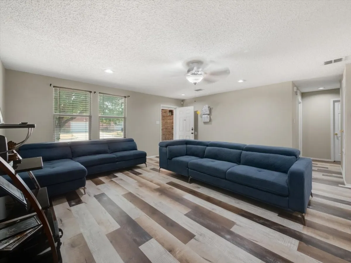 Living room featuring ceiling fan, a textured ceiling, and light wood-type flooring