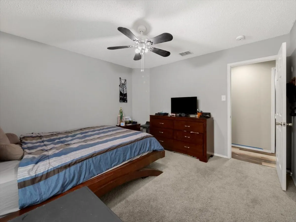 Bedroom with a textured ceiling, ceiling fan, and light colored carpet