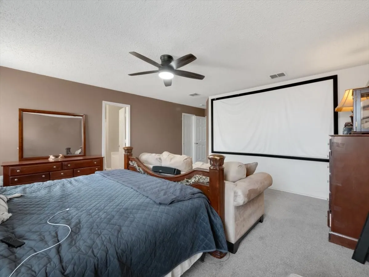 Carpeted bedroom featuring ceiling fan and a textured ceiling